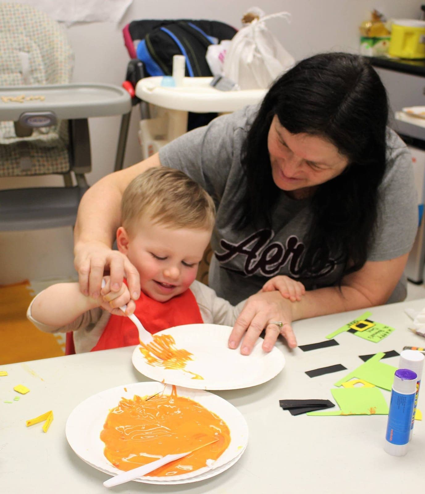 A warm hands-on art moment between a teacher and a toddler painting together at Kelly's Kidz Playhouse