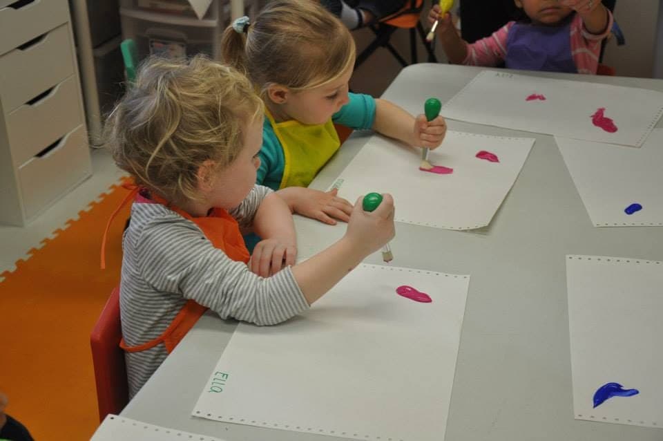 Two girls focused on their own paint-dab art projects