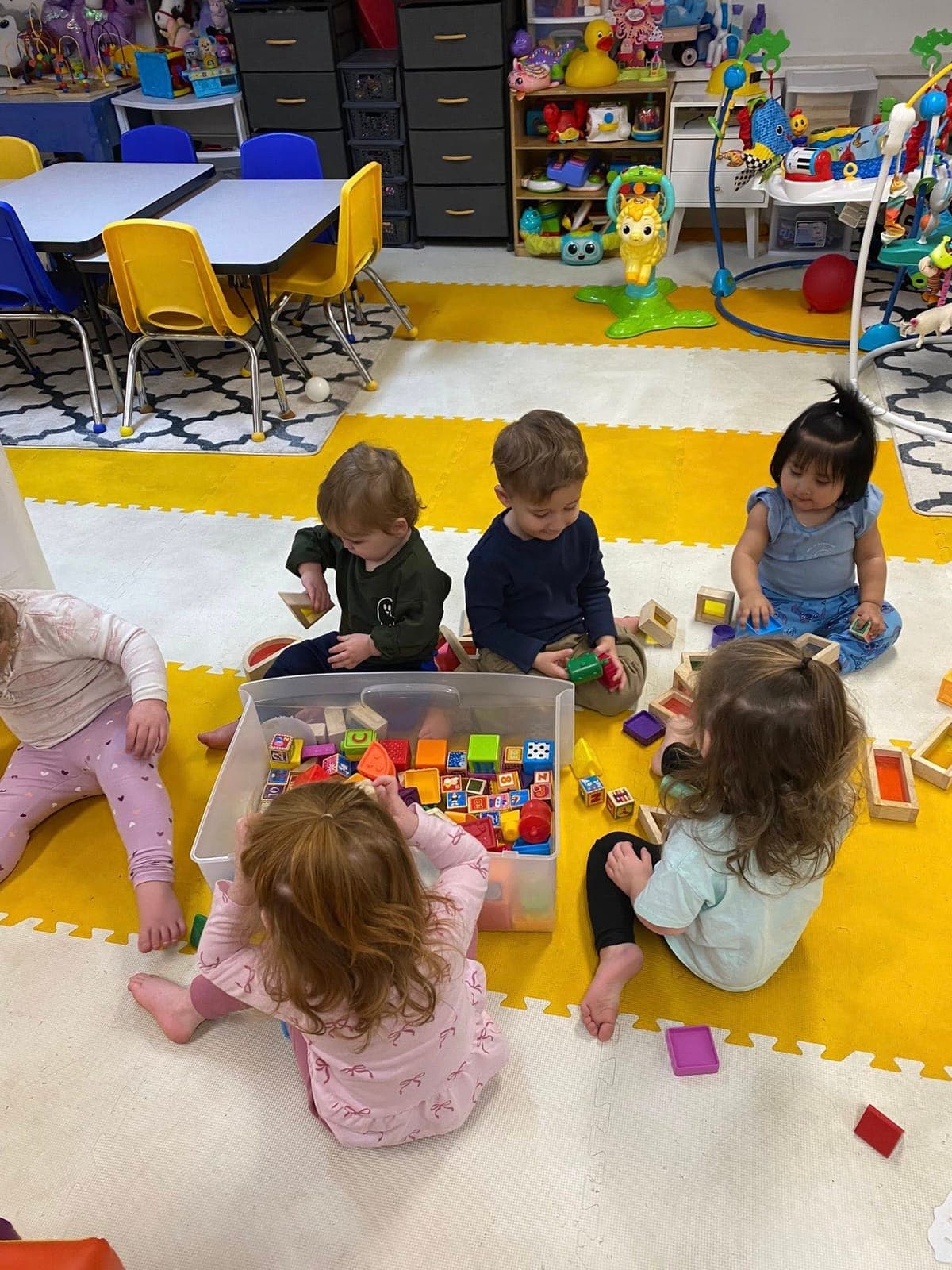 Children gathered around a bin of colorful blocks, building together at Kelly's Kidz Playhouse